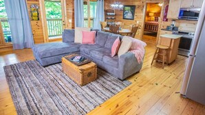 Ein gemütliches Blockhaus-Interieur mit einer Eckcouch, einem Esstisch und einer Küchenzeile.