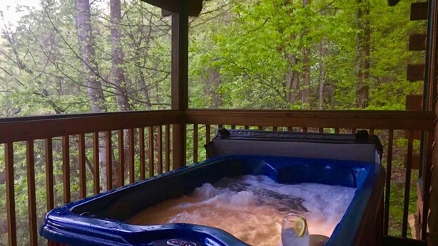 Ein Whirlpool auf einer Holzterrasse mit Blick auf einen Wald.