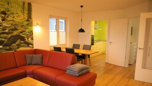 A modern living room with a red sofa, a wooden coffee table, and a dining area with a table and chairs.