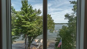 A view of a lake with dock and American flag, surrounded by trees. - Deep Creek Escape w/ Dock, Hot Tub & Views (Oakland)