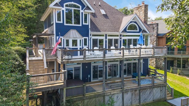 A two-story house with a deck, a swimming pool, and a flag. - Deep Creek Escape w/ Dock, Hot Tub & Views (Oakland)