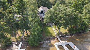 A house surrounded by dense trees, a dock, and a small bridge. - Deep Creek Escape w/ Dock, Hot Tub & Views (Oakland)