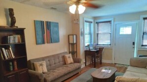 Ein Wohnzimmer mit Sofa, Couchtisch, Bücherregal und Kunstwerken an der Wand.
