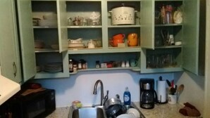 Una cucina con pensili aperti che espongono stoviglie, pentole e utensili.