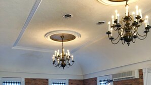 A spacious dining area with a chandelier, brick walls, and a fireplace. - National Historic Landmark Inn (Lansing)