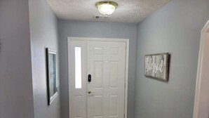 A hallway with a white door, a framed picture on the left, and a 'Blessed' sign on the right wall. - Near Ft. Moore - Ft. Benning 4 br 2 bath renovated charming home  (Columbus)