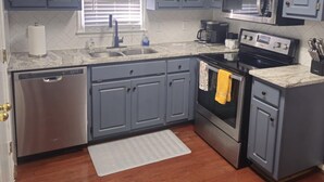A kitchen with grey cabinets, a stainless steel dishwasher, a microwave, and an oven. - Near Ft. Moore - Ft. Benning 4 br 2 bath renovated charming home  (Columbus)