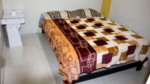 A bed with a patterned bedspread, a bedside table, and a wall with a yellow stripe.