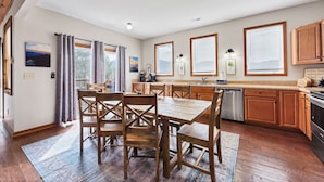 Una cocina moderna con armarios de madera, una mesa de comedor con sillas y ventanas amplias.