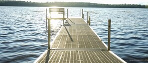 Een houten steiger die zich uitstrekt over kalm water, met een metalen looppad.