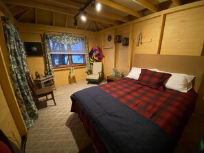 Een knus ingerichte kamer met een bed, een stoel, een bureau en een raam met gordijnen.