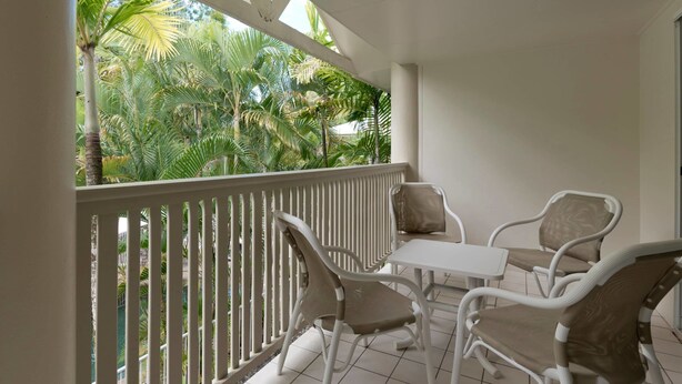 A balcony with white railings, two white chairs, and a small table.
