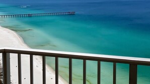 Une plage aux eaux turquoise et limpides, avec une jetée qui s’avance dans la mer.