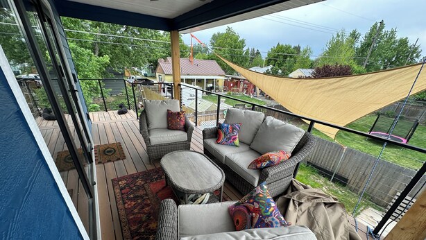 A covered deck with wicker furniture, a patterned rug, and a view of a residential area. - Upstairs, downtown Boise, private, close to green belt and Boise State. (Boise)