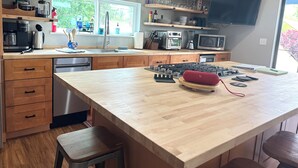 A modern kitchen with wooden cabinets, a large island, a built-in microwave, and a window providing natural light. - Upstairs, downtown Boise, private, close to green belt and Boise State. (Boise)
