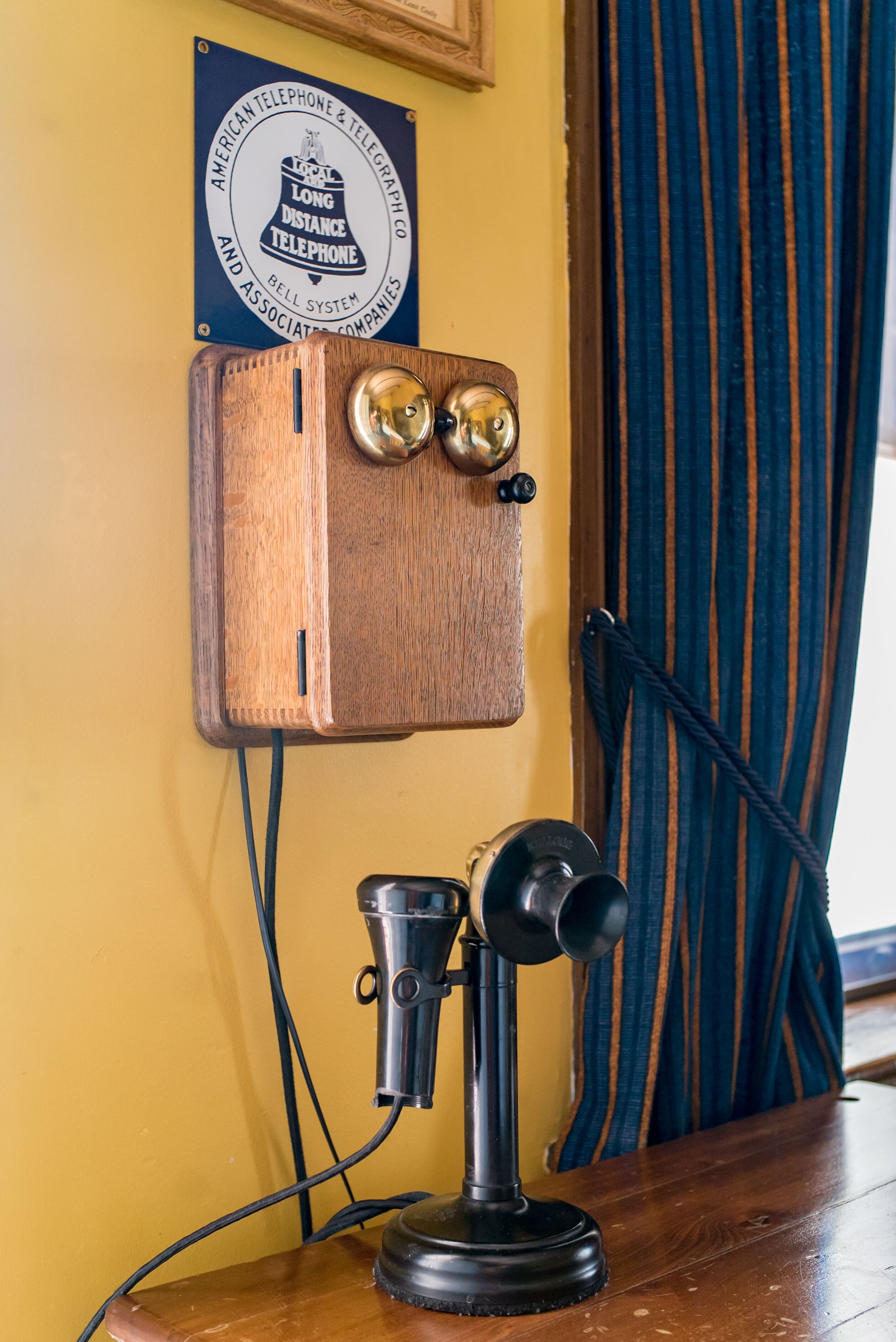Une cabine téléphonique en bois, avec une enseigne au-dessus, un microphone et un rideau en arrière-plan.