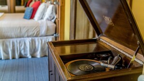 Een kamer met een bed, een houten kast met platenspeler en een spiegel die de kamer weerspiegelt.