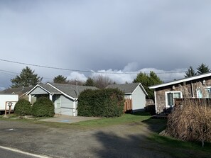 A row of single-story mobile homes with a grassy yard and a cloudy sky. - Sand Bucket Cottage (Pacific Beach)