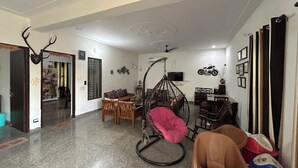 Un amplio salón con techo alto, un sillón colgante, una mesa de comedor y un televisor.