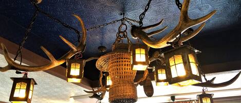 A chandelier with antlers and lanterns hanging from the ceiling.