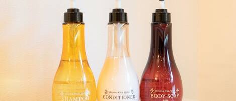 Three bottles of personal care products: shampoo, conditioner, and body soap.