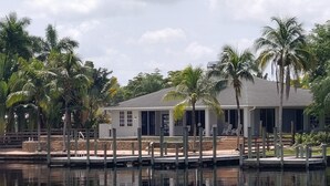 Une propriété située au bord de l’eau, dotée d’un patio couvert, de palmiers et donnant sur une étendue d’eau calme.