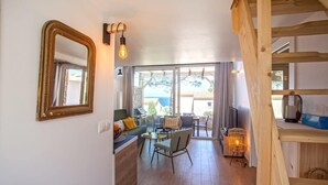 Un espacio de sala acogedor con un sofá, sillas, una mesa de centro y una escalera de madera.
