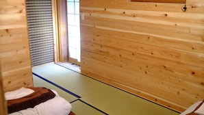 A traditional Japanese room with tatami flooring, wooden walls, and a sliding door. - Hakone Guesthouse toi - Hostel (Hakone)