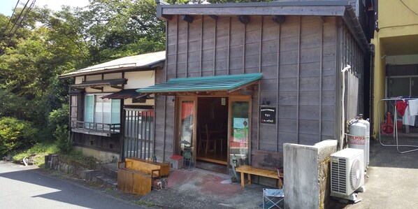 A guesthouse with a wooden exterior, a green awning, and a bench outside. - Hakone Guesthouse toi - Hostel (Hakone)