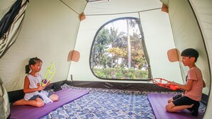 Une tente avec deux tapis violets à l’intérieur, une fenêtre et une vue sur les arbres à l’extérieur.