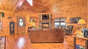 Ein gemütliches Blockhaus-Interieur mit Kamin aus Stein, Ledersofa und Holzwänden.