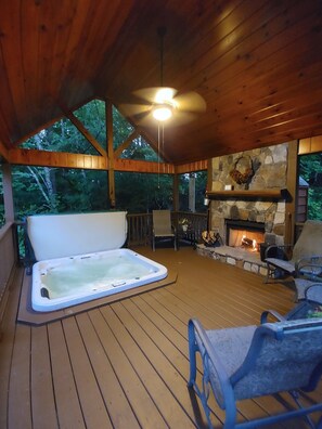 A wooden deck with a hot tub, stone fireplace, and outdoor seating. - WoodHaven: Secluded Creekside Cabin | Blue Ridge, GA | Hot Tub & Modern Comforts (Mineral Bluff)