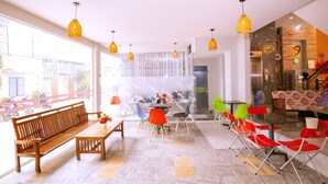 A modern interior with a wooden bench, colorful chairs, a table, and hanging pendant lights.