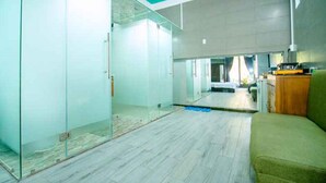 A modern office space with glass partitions, a wooden floor, and a green couch.