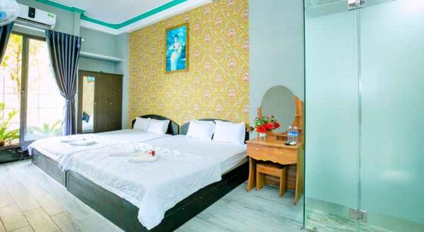 Ein Hotelzimmer mit einem großen Bett, einem Holznachttisch, einem Spiegel und einem Fenster mit Vorhängen.