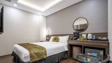 Ein Hotelzimmer mit Bett, Nachttisch, Spiegel und einem kleinen runden Tisch mit Glasplatte.