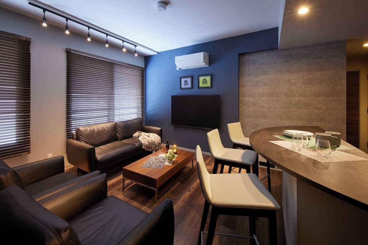 A modern living room with a leather sofa, a coffee table, and a dining area with a bar.