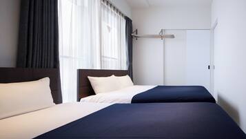 A hotel room with a bed, a wardrobe, and a window with curtains.