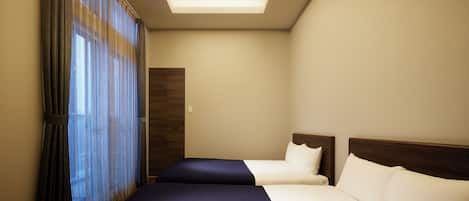 Habitación de hotel con dos camas, un tragaluz y un amplio ventanal con cortinas.