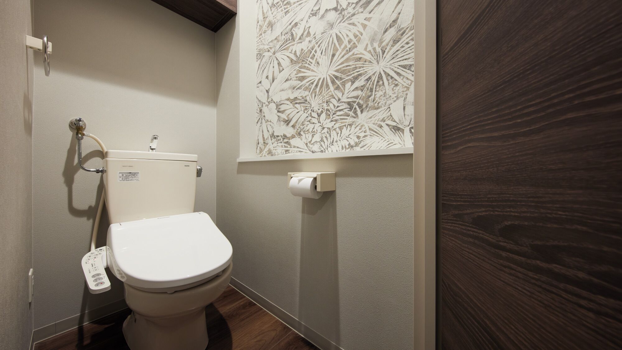 Un baño moderno con un inodoro, un dispensador de papel higiénico y un perchero de toallas en la pared.