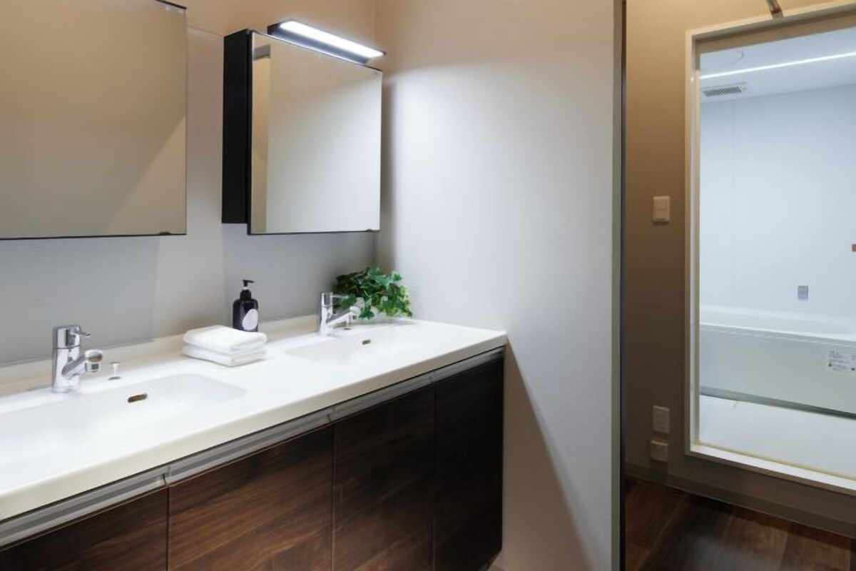 A modern bathroom with two sinks, a mirror, and a shower.