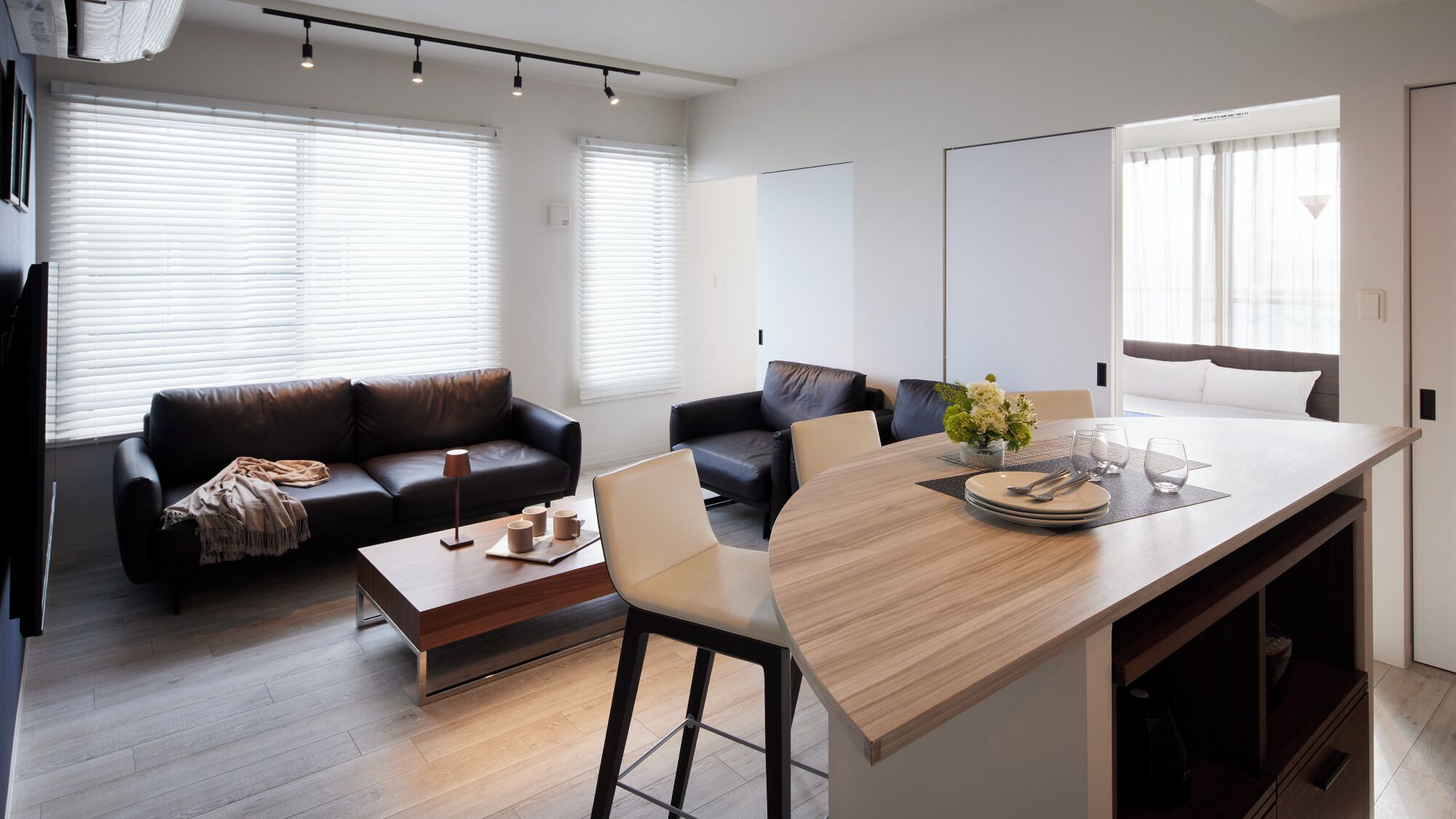 A modern living room with a sofa, a coffee table, and a dining area with a table and chairs.