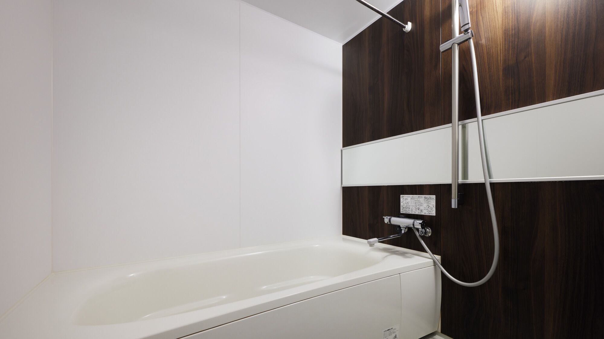 A modern bathroom with a white bathtub, a wooden panel wall, and a wall-mounted shower.