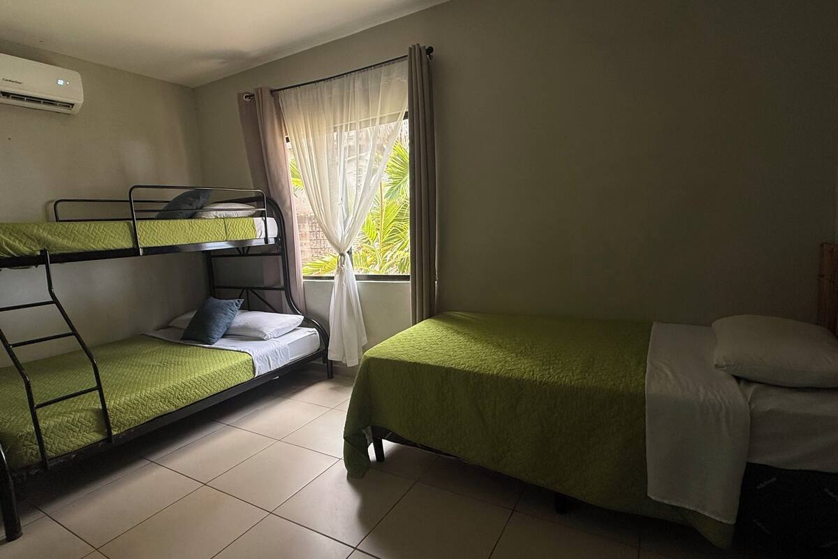 A room with bunk beds, a window with curtains, and an air conditioning unit.
