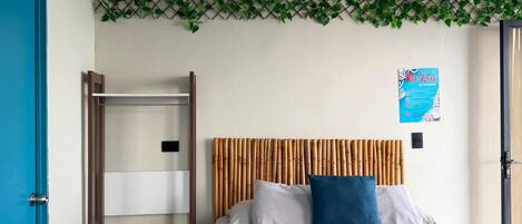 A bedroom with a bed, a wardrobe, a hanging chair, and a wall-mounted plant.