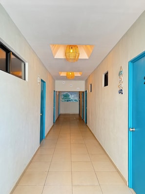A hotel hallway with blue doors, a tiled floor, and a ceiling light fixture.