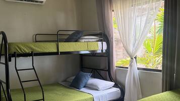 Une chambre avec des lits superposés, une fenêtre avec des rideaux, un radiateur et une petite table.