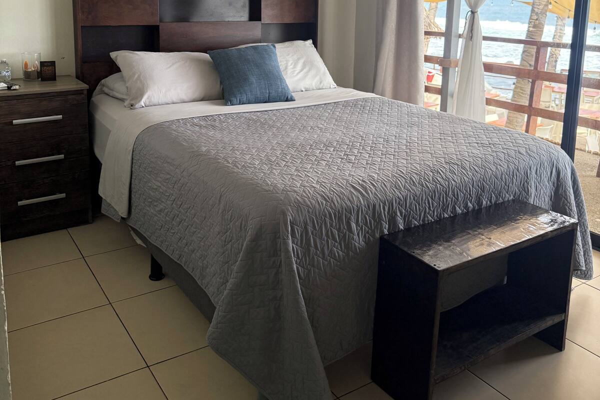 A bedroom with a bed, bedside table, and curtains.