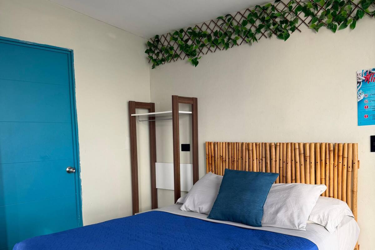 A bed with a blue blanket, white pillows, and a bamboo headboard.