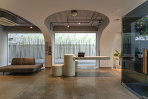 A reception area with a sofa, a reception desk, and a glass wall. - MEANDER Saigon (Ho Chi Minh City)
